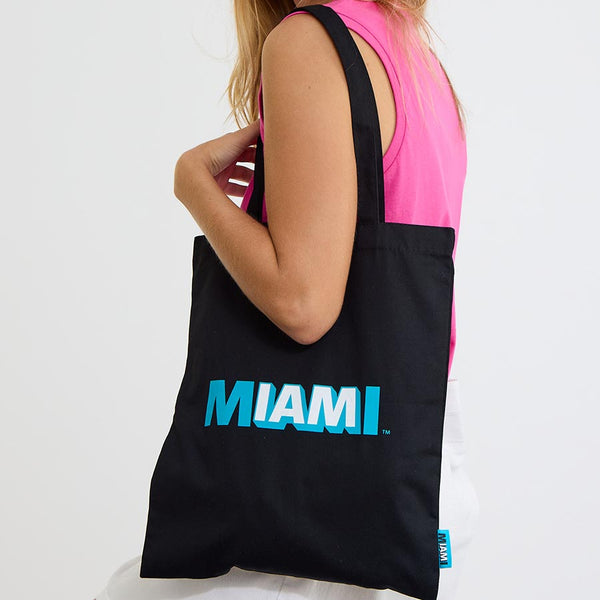 Woman carrying the black Coral Miami tote bag over her shoulder